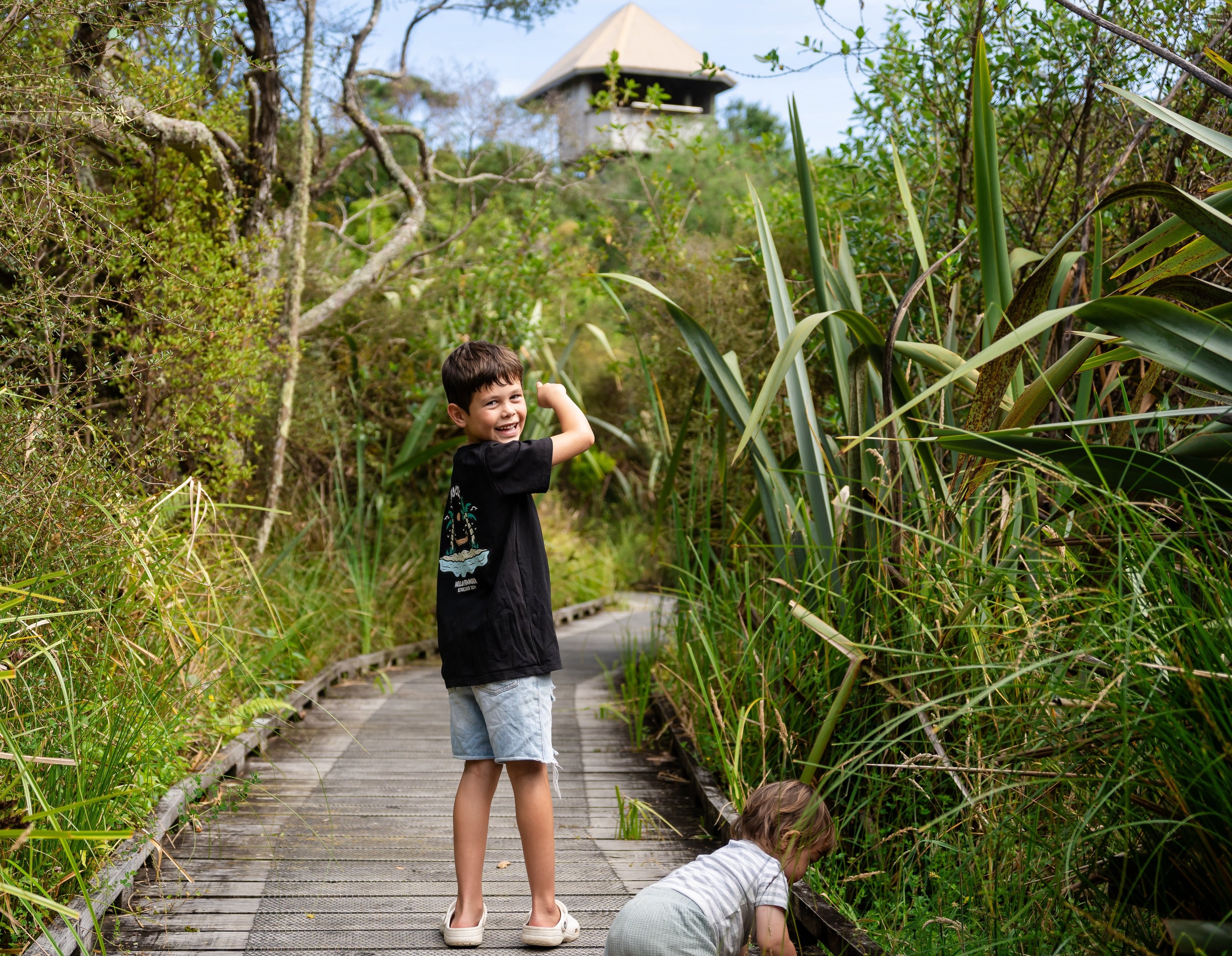 kids on the bush walk trail pointing towards Piki's Perch lookout tower at Ngā Manu nature reserve in Waikanae on the Kāpiti coast.